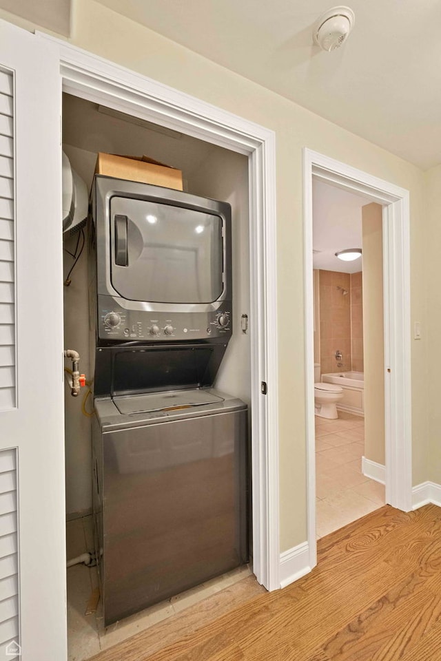 laundry room with laundry area, stacked washer and dryer, and baseboards