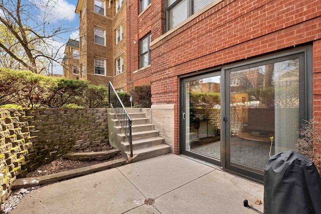 property entrance with brick siding and a patio