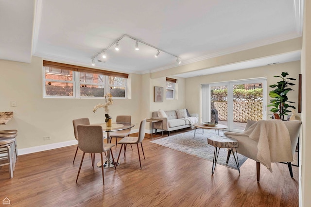 dining room with track lighting, baseboards, ornamental molding, and wood finished floors