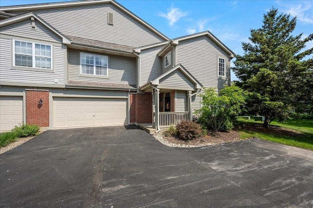multi unit property featuring an attached garage, driveway, and brick siding
