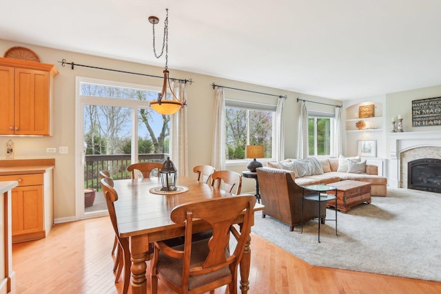 34457 N Bluestem Rd, Round Lake, IL 60073 - dining area featuring a glass covered fireplace, built in features, a healthy amount of sunlight, and light wood-style flooring