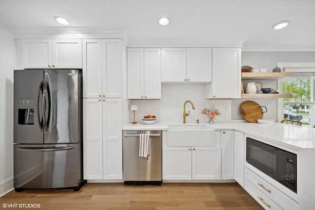 kitchen with appliances with stainless steel finishes, a sink, white cabinetry, open shelves, and light wood-type flooring