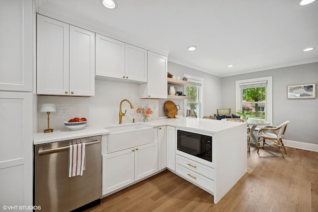 kitchen featuring stainless steel dishwasher, a sink, black microwave, a peninsula, and crown molding