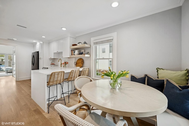 dining area with crown molding, light wood-style flooring, visible vents, and recessed lighting