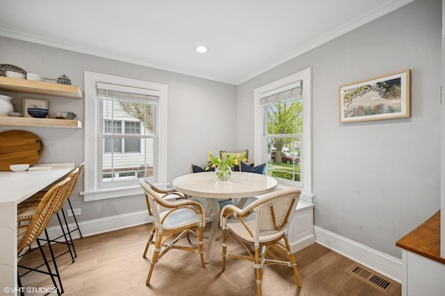 dining room with baseboards, a wealth of natural light, ornamental molding, and visible vents