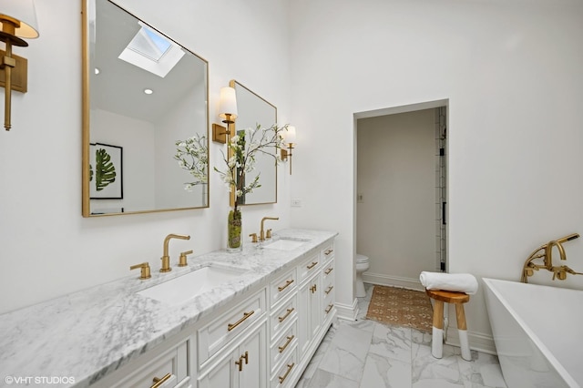 full bath featuring toilet, marble finish floor, a sink, and a skylight