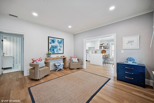 sitting room featuring crown molding, light wood finished floors, and visible vents