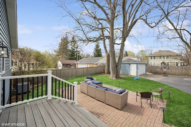 wooden deck with a yard, fence, a detached garage, and an outdoor hangout area