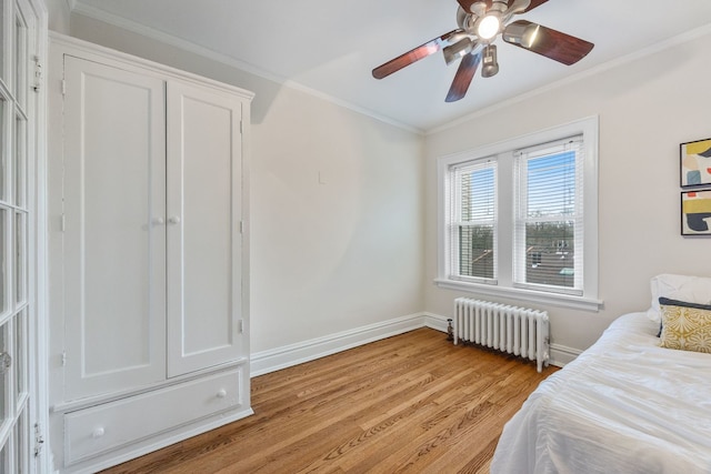 bedroom with radiator, baseboards, light wood-style floors, ceiling fan, and ornamental molding
