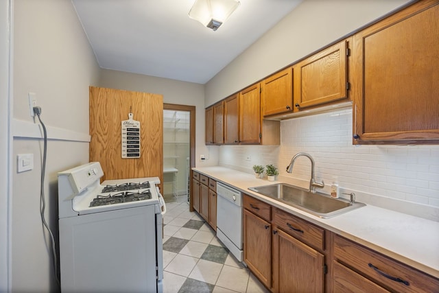 kitchen with a sink, tasteful backsplash, white appliances, brown cabinets, and light countertops