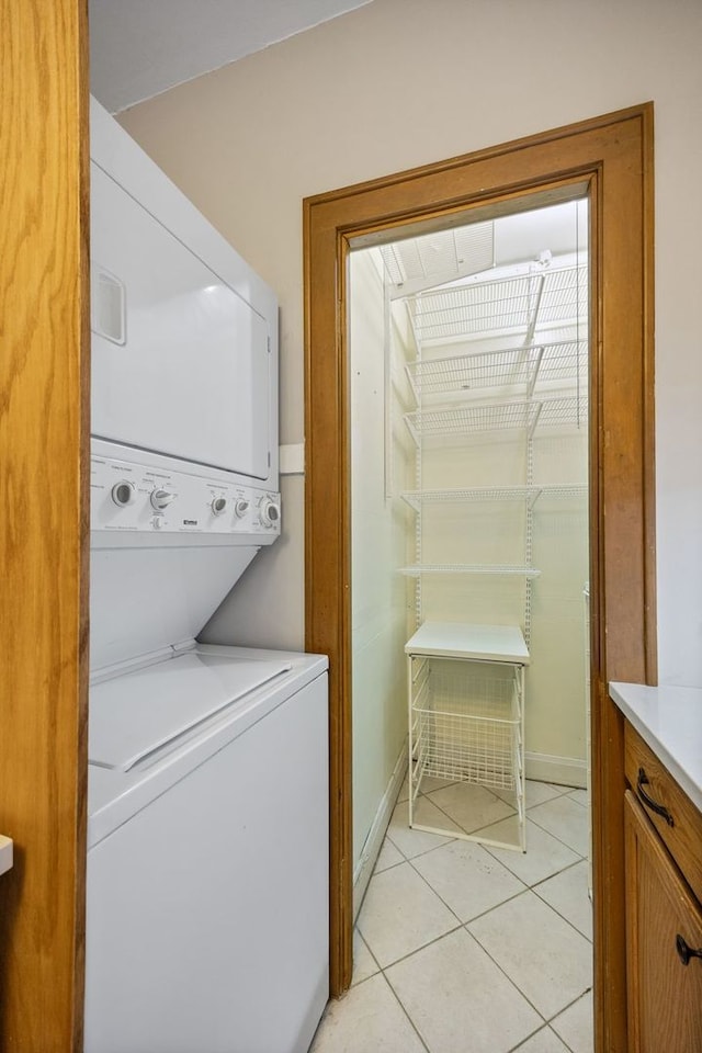 washroom with stacked washer and clothes dryer, laundry area, and light tile patterned floors