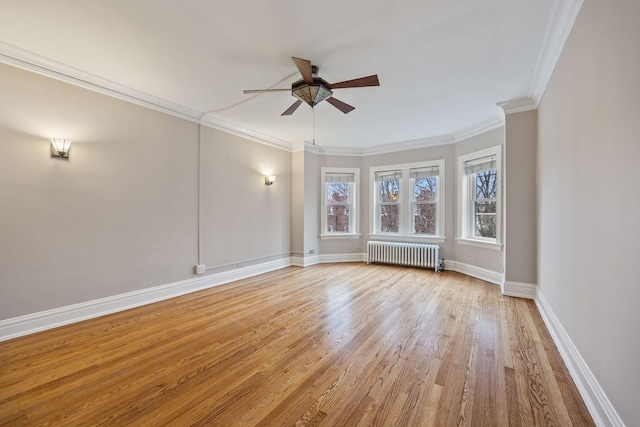 empty room featuring radiator heating unit, light wood finished floors, ornamental molding, baseboards, and ceiling fan
