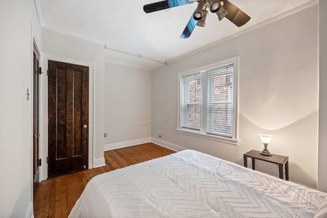 bedroom with baseboards, wood finished floors, ornamental molding, and ceiling fan