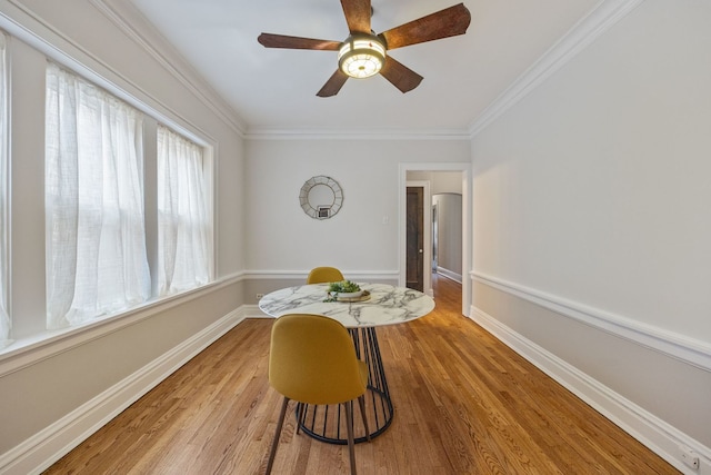 dining area featuring light wood-style floors, crown molding, baseboards, and ceiling fan