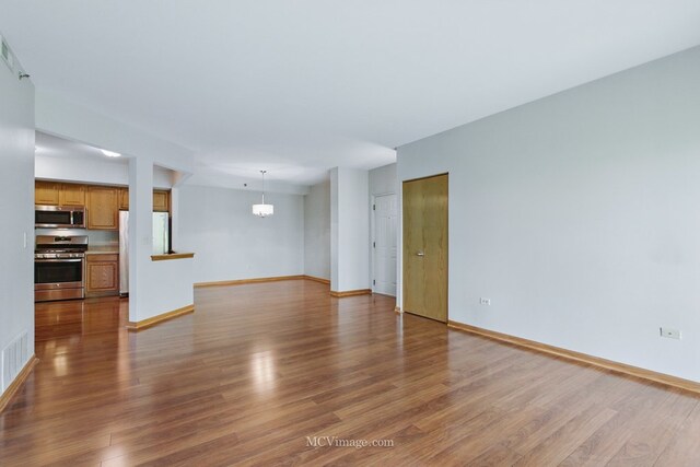7841 W 157th St Unit 303, Orland Park, IL 60462 - unfurnished living room featuring wood finished floors, baseboards, and a chandelier