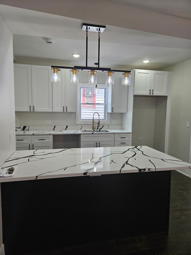 kitchen featuring hanging light fixtures, light countertops, white cabinets, and a sink