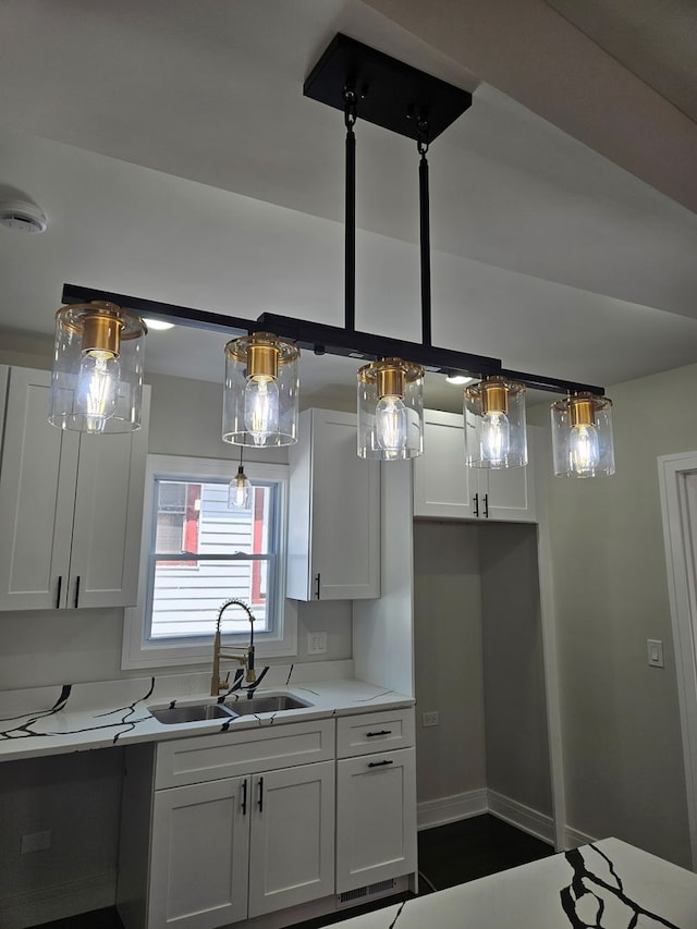 kitchen with baseboards, light countertops, white cabinets, and a sink