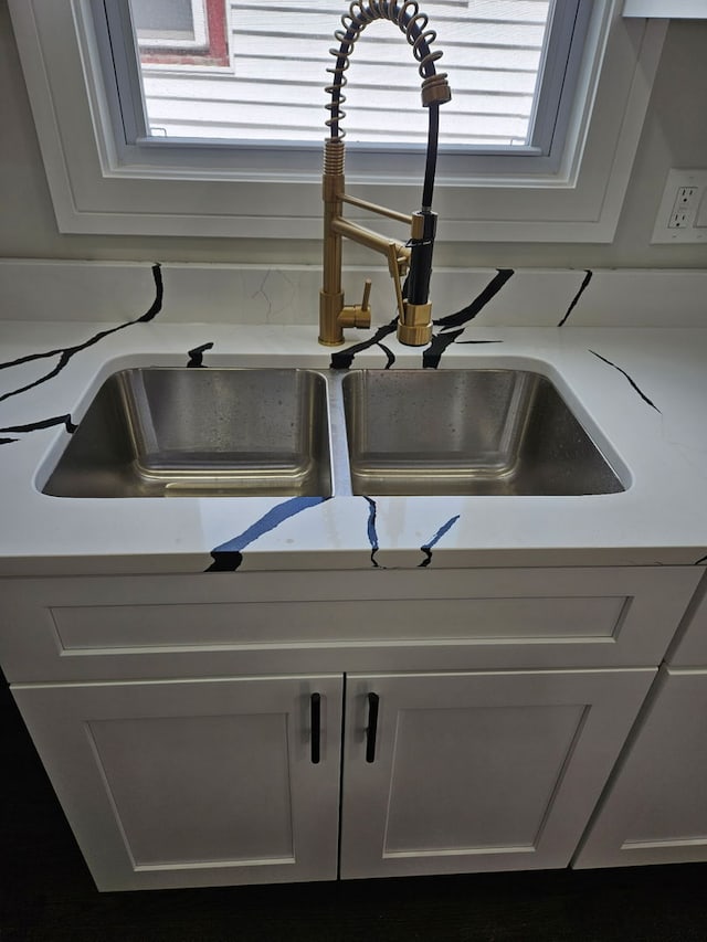 interior details with a sink, white cabinetry, and light countertops