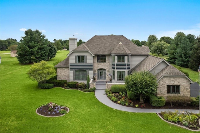 french provincial home with a chimney, stone siding, and a front yard