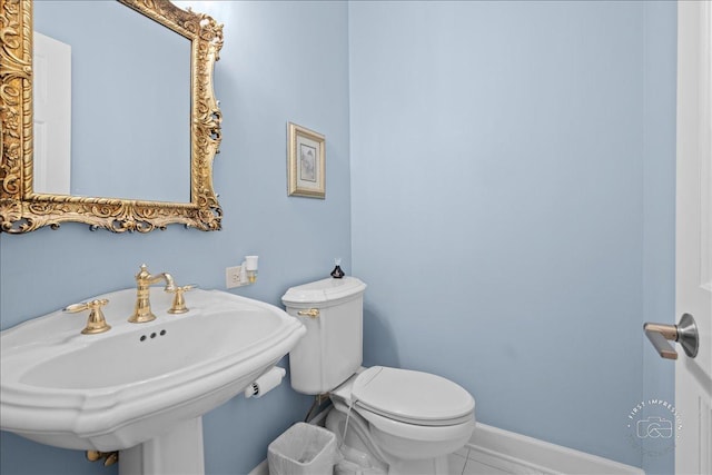 half bath with a sink, baseboards, and toilet