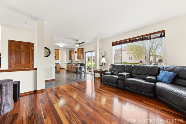 living area with a ceiling fan and dark wood-style flooring