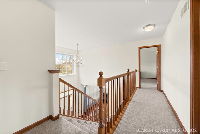 hall with an upstairs landing, a chandelier, carpet floors, baseboards, and visible vents