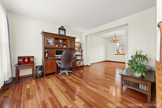 home office with light wood finished floors, baseboards, visible vents, and a notable chandelier