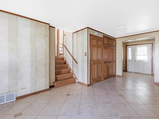 foyer with baseboards, visible vents, and stairway