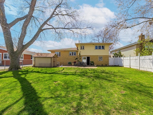 back of property with a fenced backyard, a shed, an outdoor structure, a patio, and brick siding