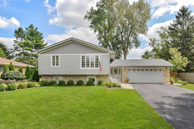 split level home featuring a garage, a front lawn, fence, and driveway