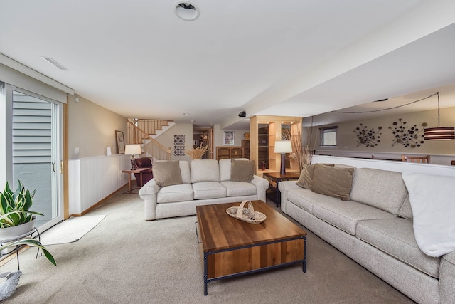 living area featuring stairway, a wainscoted wall, carpet flooring, and visible vents