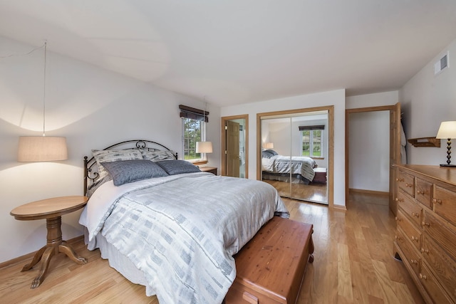 bedroom with visible vents, light wood finished floors, a closet, and multiple windows