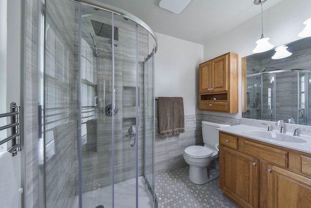 bathroom with vanity, toilet, tile walls, a wainscoted wall, and a shower stall