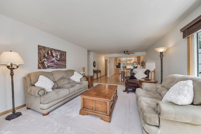 living area with baseboards, ceiling fan, and carpet