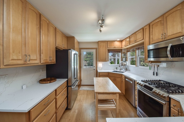 kitchen with plenty of natural light, light wood-style flooring, backsplash, and stainless steel appliances
