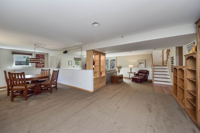 carpeted dining area with stairway, baseboards, and plenty of natural light