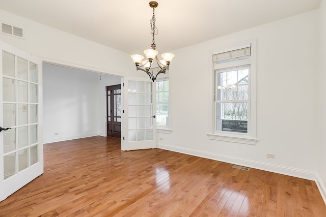 interior space featuring baseboards, a chandelier, visible vents, and light wood-style floors