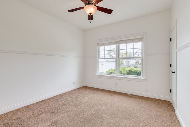 spare room with baseboards, visible vents, light colored carpet, and ceiling fan