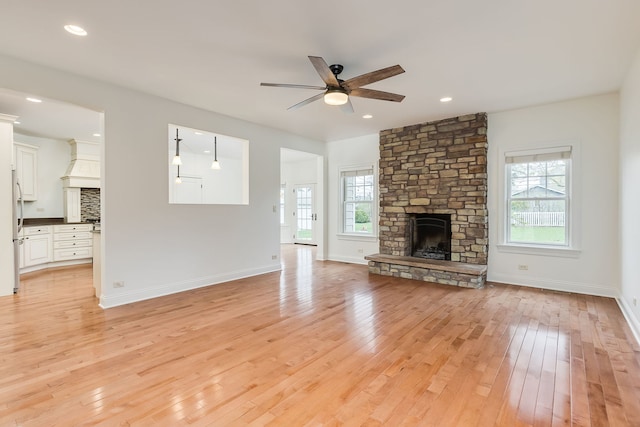 unfurnished living room featuring light wood-type flooring, ceiling fan, a fireplace, baseboards, and recessed lighting