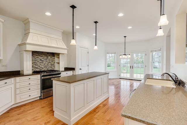 kitchen featuring a sink, light wood-type flooring, recessed lighting, backsplash, and gas range