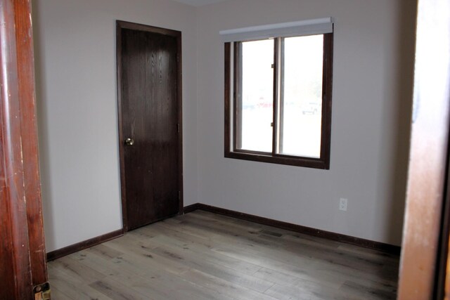 unfurnished bedroom featuring light wood-type flooring, baseboards, and a closet