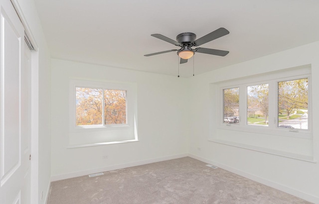 unfurnished room with light carpet, baseboards, visible vents, and ceiling fan