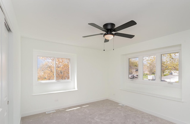 unfurnished room featuring light carpet, a ceiling fan, baseboards, and a healthy amount of sunlight