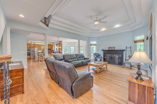 3908 Royal Portrush Dr, Naperville, IL 60564 - living area with ceiling fan, a tray ceiling, light wood-style floors, a fireplace, and decorative columns