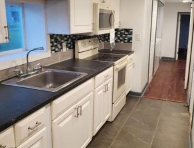 555 E 88th Pl, Chicago, IL 60619 - kitchen featuring white cabinets, a sink, stainless steel microwave, backsplash, and electric stove