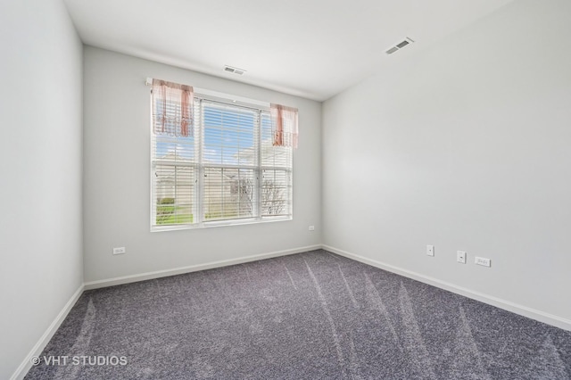 unfurnished room featuring visible vents, baseboards, plenty of natural light, and dark carpet