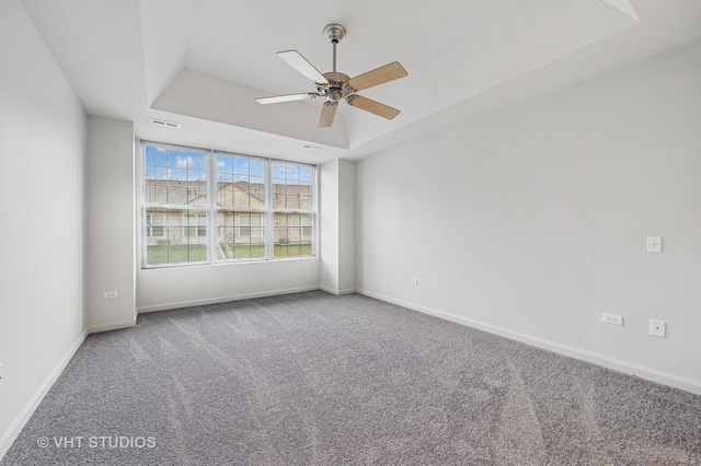 carpeted spare room featuring baseboards, a raised ceiling, and ceiling fan