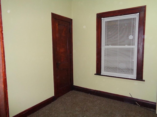 spare room with dark carpet and baseboards