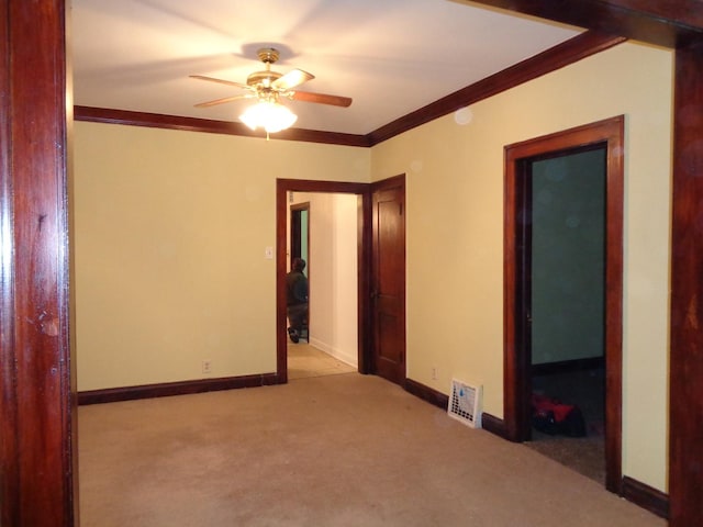 spare room with carpet, visible vents, a ceiling fan, crown molding, and baseboards