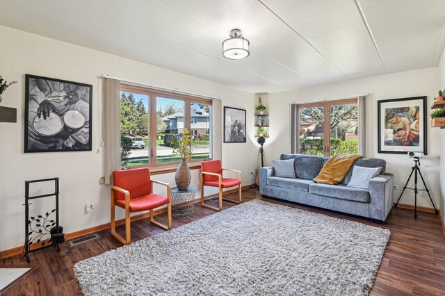 living room featuring baseboards, dark wood-type flooring, and visible vents